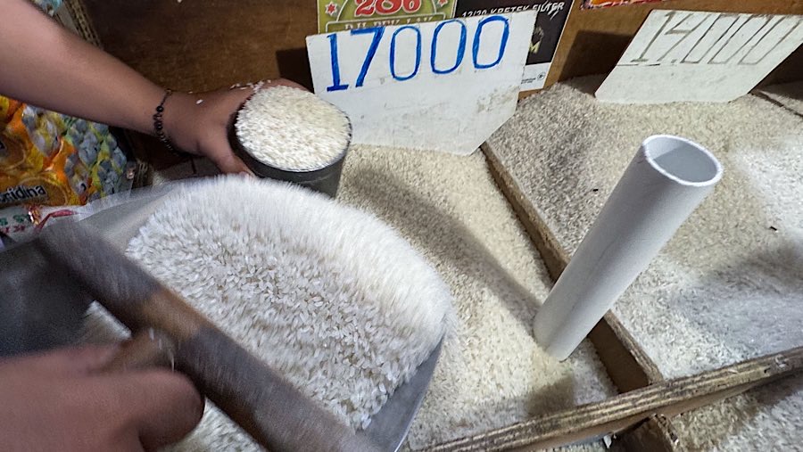 Pedagang menuangkan beras di salah satu warung sembako di kawasan Jati Padang, Jakarta, Selasa (12/8/2025) (Bloomberg Technoz/Andrean Kristianto)