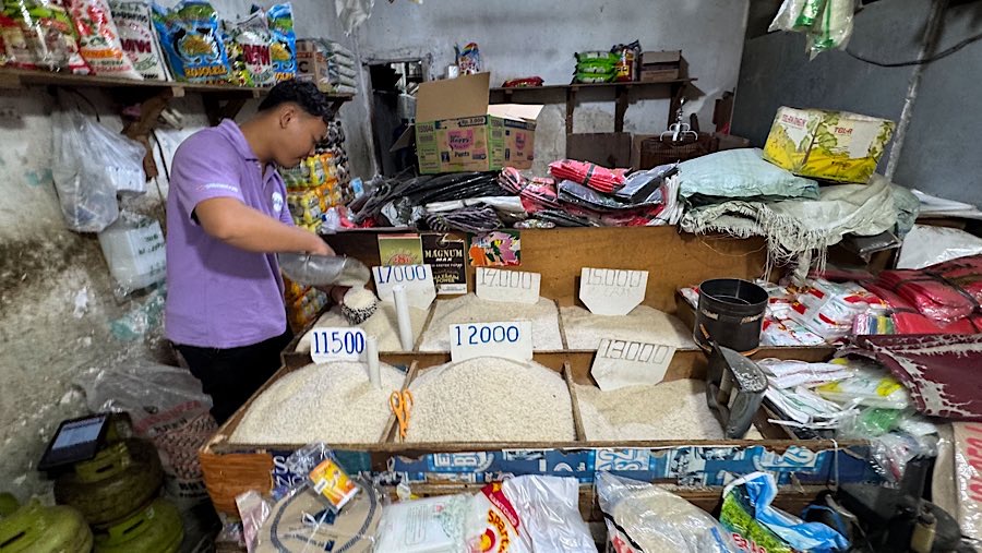 Pedagang menuangkan beras di salah satu warung sembako di kawasan Jati Padang, Jakarta, Selasa (12/8/2025) (Bloomberg Technoz/Andrean Kristianto)