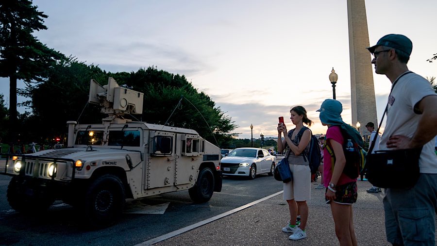Warga mengambil foto kendaraan lapis baja di dekat Monumen Washington di Washington, DC, AS, Selasa (12/7/2025).(Stefani Reynolds/Bloomberg)