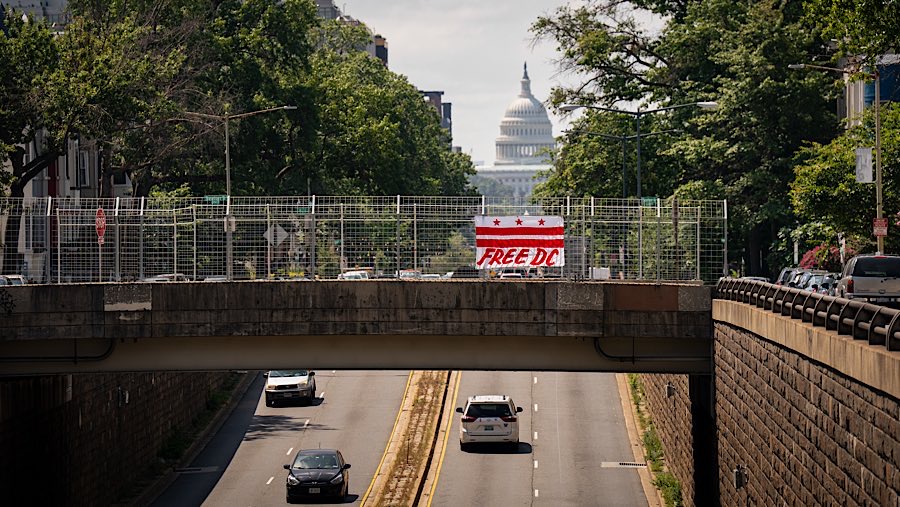 Bendera Free DC di sebuah jembatan dekat Gedung Capitol AS di Washington, DC, AS, Selasa (12/7/2025). (Al Drago/Bloomberg)