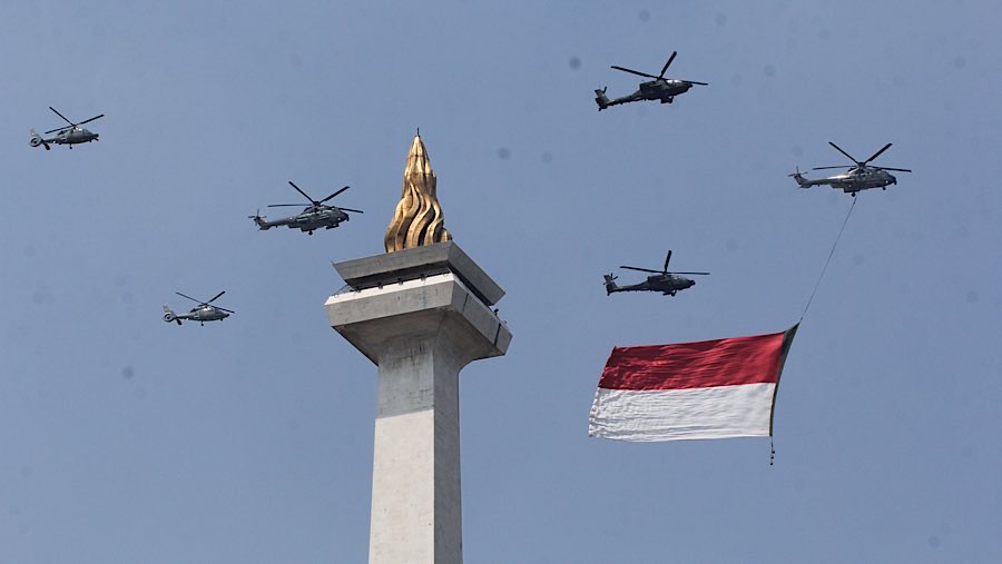 Sebanyak 8 helikopter TNI, dari AU dan AD, mengibarkan bendera raksasa merah putih yang membentang. (Bloomberg Technoz/Andrean Kristianto)