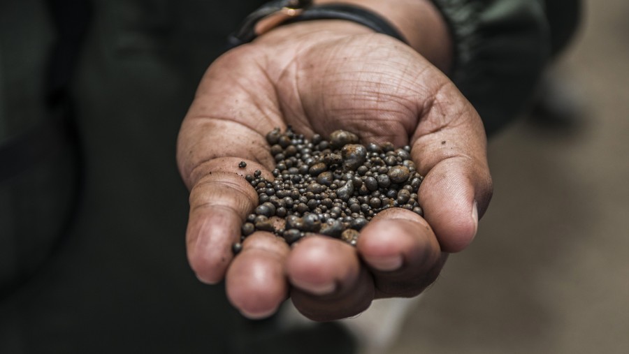 Seorang pekerja tambang memegang bongkahan logam kobalt yang menunggu pengiriman di Chingola, Zambia. Fotografer: Waldo Swiegers/Bloomberg