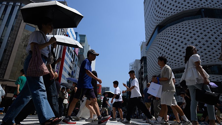 Pejalan kaki menyeberang jalan di distrik Ginza saat suhu tinggi melanda Tokyo, Jepang, Minggu (24/8/2025). (Akio Kon/Bloomberg)