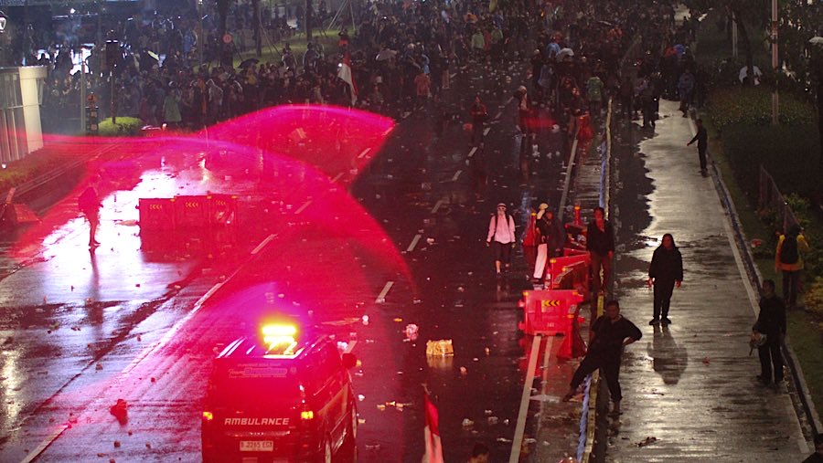 Meskipun diguyur hujan, massa tetap bertahan disekitar Polda Metro Jaya. (Bloomberg Technoz/Andrean Kristianto)