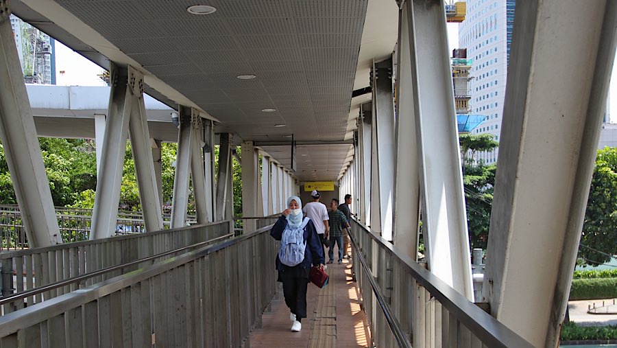 Pejalan kaki menyeberang jalan melalui JPO Dukuh Atas, Jakarta, Selasa (2/9/2025). (Bloomberg Technoz/Andrean Kristianto)
