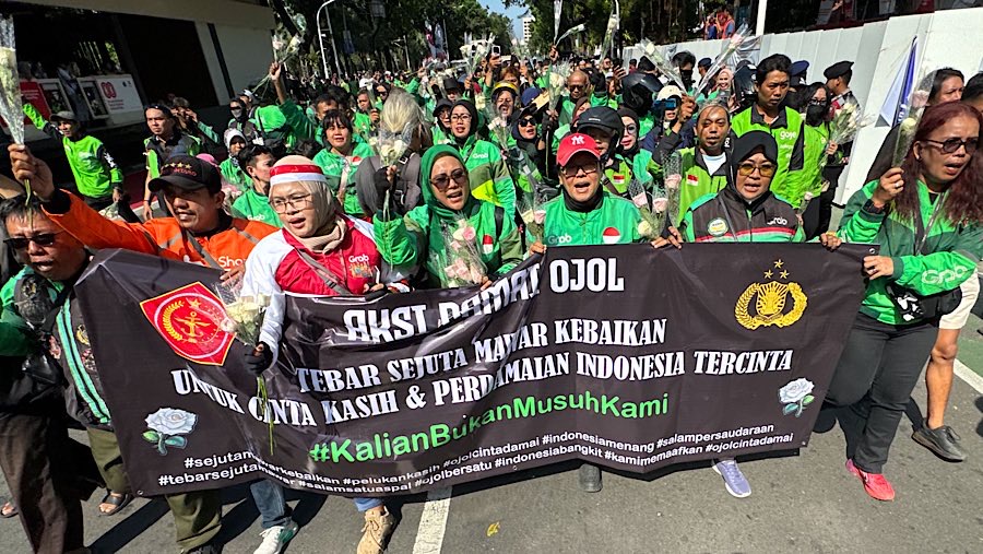 Sejumlah driver ojol melakukan aksi damai mambagikan bunga di jalan Medan Merdeka Selatan, Selasa (2/9/2025). (Bloomberg Technoz/Andrean Kristianto)