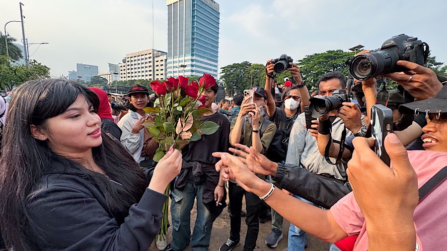 Salah satu peserta aksi terlihat membagikan bunga mawar kepada peserta aksi lainny.  (Bloomberg Technoz/Andrean Kristianto)