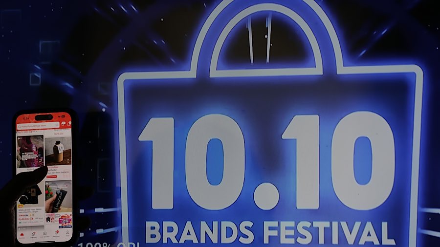 Warga membuka aplikasi belanja daring dengan latar iklan Harbolnas 10.10 di Jakarta, Senin (8/9/2025). (Bloomberg Technoz/Andrean Kristianto)