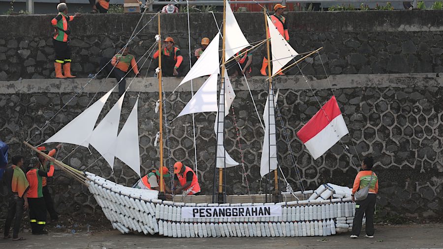 Petugas UPS Badan Air menurunkan perahu dari limbah botol di Kali Ciliwung, Cikoko, Jakarta, Selasa (23/9/2025) (Bloomberg Technoz/Andrean Kristianto)