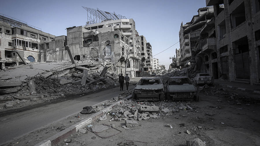 Warga berjalan diantara bangunan dan mobil yang rusak karena serangan Israel di Kota Gaza, Gaza, Senin (29/9/2025). (Ahmad Salem/Bloomberg)