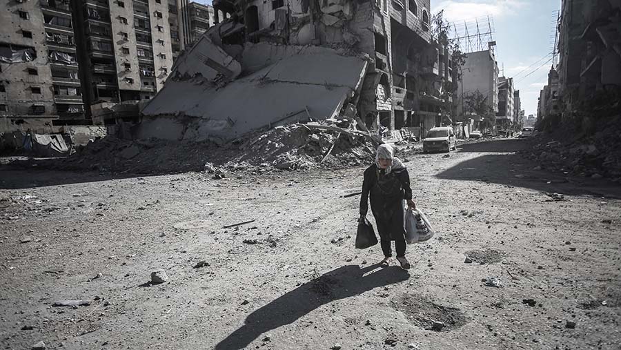 Warga Palestina berjalan melewati reruntuhan bangunan yang hancur di Kota Gaza, Gaza, Senin (29/9/2025). (Ahmad Salem/Bloomberg)