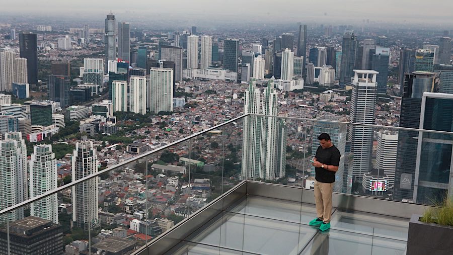 Pengunjung menikmati landskap gedung bertingkat Jakarta di UP at Thamrin Nine, Jakarta, Kamis (2/10/2025). (Bloomberg Technoz/ Andrean Kristianto)