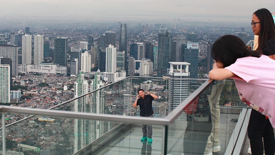 Pengunjung menikmati landskap gedung bertingkat Jakarta di UP at Thamrin Nine, Jakarta, Kamis (2/10/2025). (Bloomberg Technoz/ Andrean Kristianto)