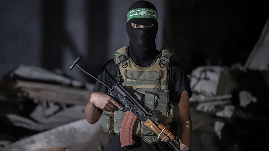 Sayap militer Hamas, memantau kendaraan IRCC saat mengumpulkan jenazah sandera Israel di Kota Gaza, Gaza, Rabu (15/10/2025). (Ahmad Salem/Bloomberg)