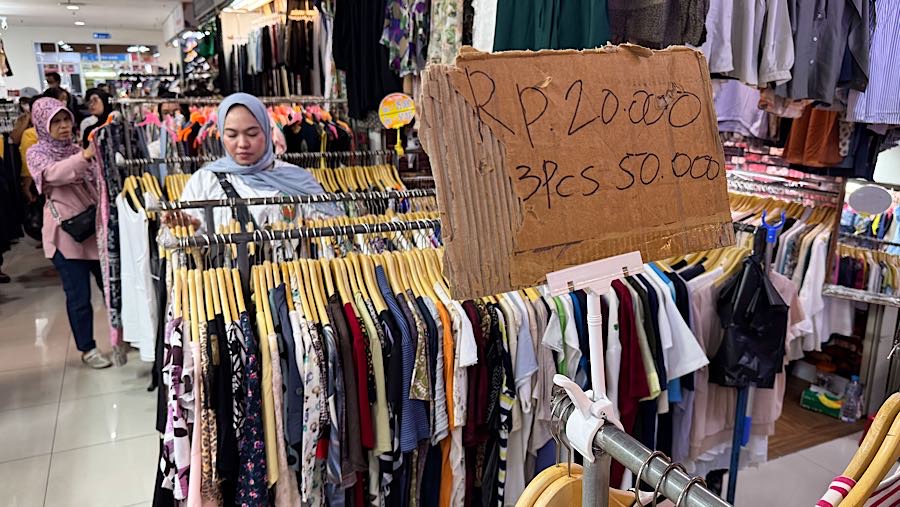 Colon pembeli melihat baju thrift (pakaian bekas impor) di Pasar Jaya Senen, Jakarta, Kamis (23/10/2025). (Bloomberg Technoz/Andrean Kristianto)