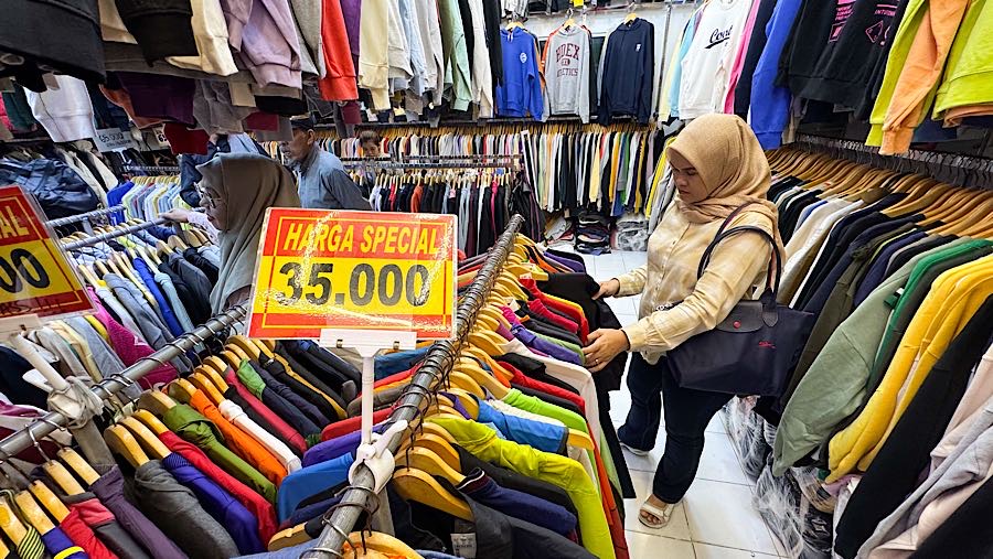 Colon pembeli melihat baju thrift (pakaian bekas impor) di Pasar Jaya Senen, Jakarta, Kamis (23/10/2025). (Bloomberg Technoz/Andrean Kristianto)