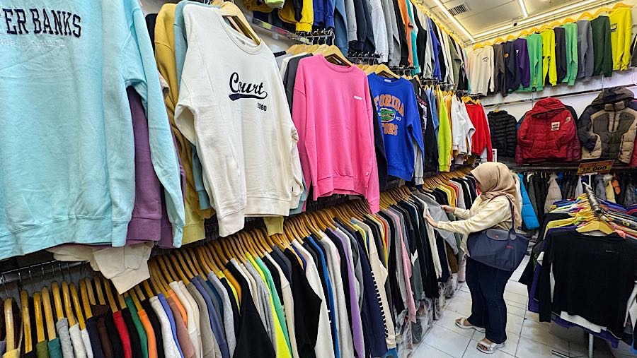 Colon pembeli melihat baju thrift (pakaian bekas impor) di Pasar Jaya Senen, Jakarta, Kamis (23/10/2025). (Bloomberg Technoz/Andrean Kristianto)