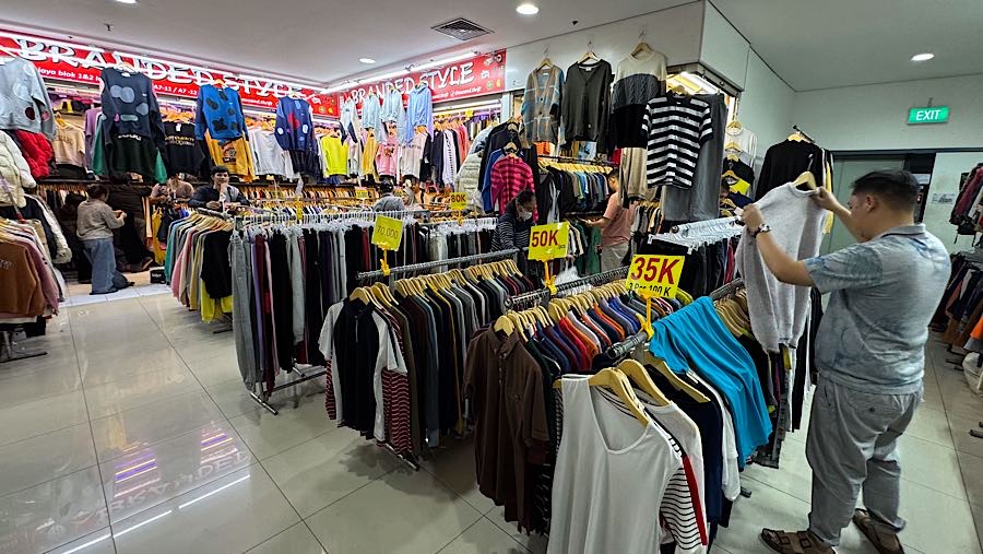 Colon pembeli melihat baju thrift (pakaian bekas impor) di Pasar Jaya Senen, Jakarta, Kamis (23/10/2025). (Bloomberg Technoz/Andrean Kristianto)