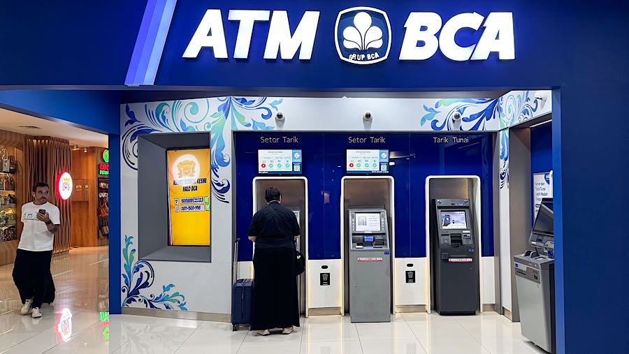 Nasabah bertransaksi di mesin ATM BCA di Bandara I Gusti Ngurah Rai, Bali, Minggu (28/9/2025). (Bloomberg Technoz/Andrean Kristianto)