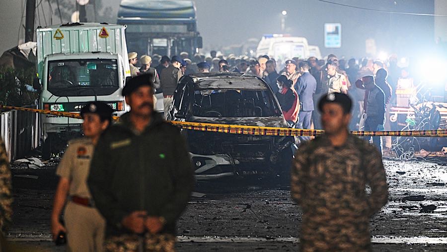 Petugas keamanan berada di dekat kendaraan yang hancur di lokasi ledakan di New Delhi, India, Senin (10/11/2025). (Prakash Singh/Bloomberg)