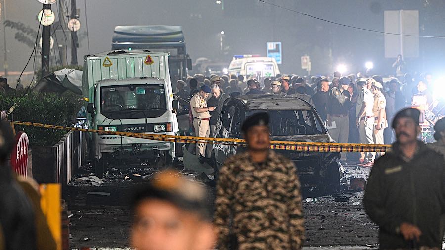 Petugas keamanan berada di dekat kendaraan yang hancur di lokasi ledakan di New Delhi, India, Senin (10/11/2025). (Prakash Singh/Bloomberg)