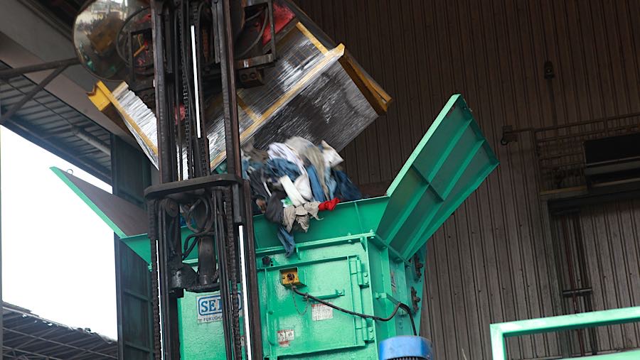 Petugas memusnahkan balpres pakaian bekas dengan mesin pencacah di PT PPLI, Bogor, Jumat (14/11/2025). (Bloomberg Technoz/Andrean Kristianto)