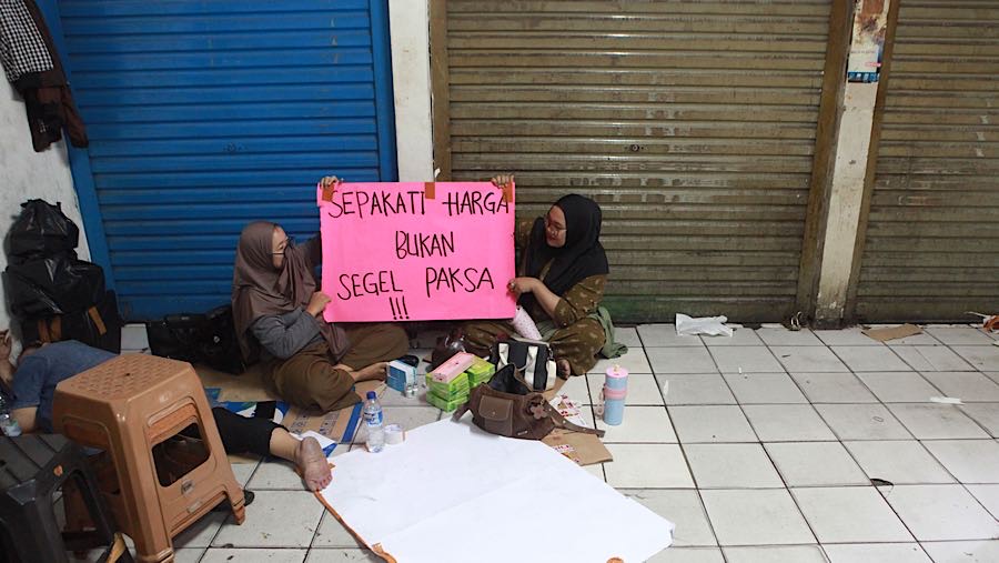 Para pekerja terlihat hanya duduk-duduk di depan kios yang tertutup. (Bloomberg Technoz/Andrean Kristianto)