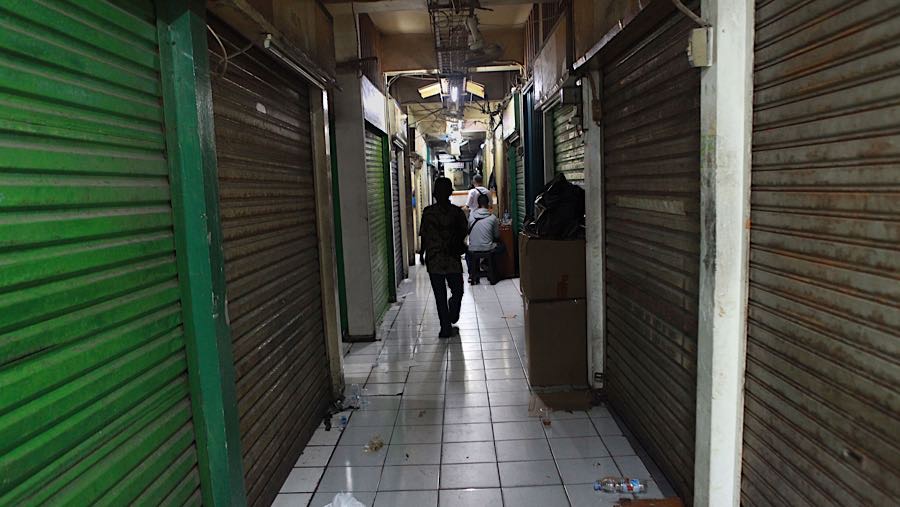 Warga berjalan di antara kios yang tutup di Pasar Pramuka, Matraman, Jakarta, Jumat (14/11/2025). (Bloomberg Technoz/Andrean Kristianto)
