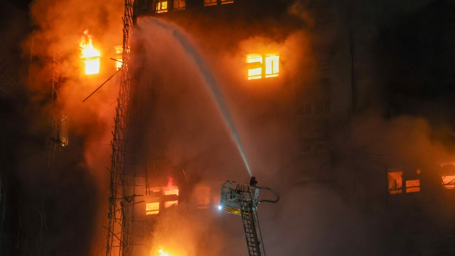 Petugas berusaha memadamkan kebakaran bangunan hunian di Hong Kong (26/11/). (Yik Yeung-man/Bloomberg)