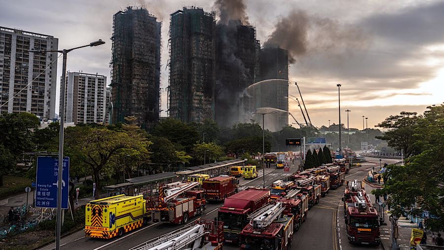 Asap mengepul dari bangunan hunian sementara api terus berkobar di Wang Fuk Court, distrik Tai Po, Hong Kong, Kamis (27/11/2025). (Lam Yik/Bloomberg)