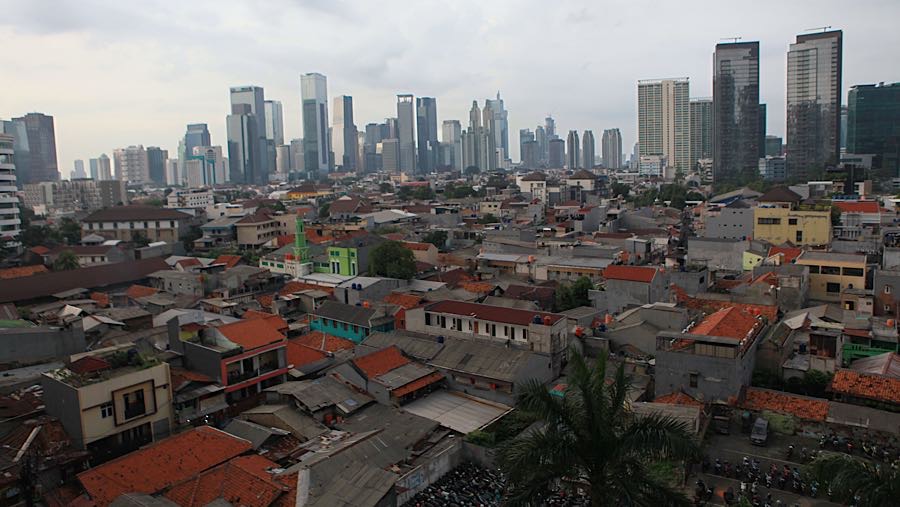 Suasana pemukiman dengan latar gedung bertingkat di Jakarta, Kamis (27/11/2025). (Bloomberg Technoz/Andrean Kristianto)