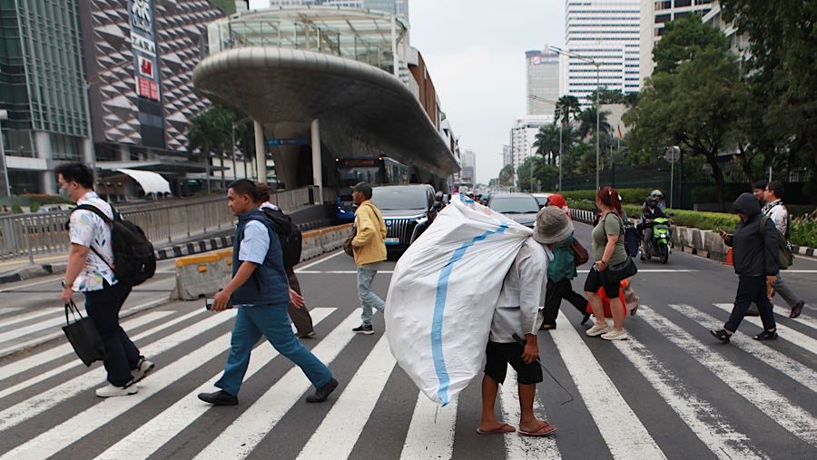 Warga menyeberang jalan di jalan Sudirman, Jakarta, Kamis (27/11/2025). (Bloomberg Technoz/Andrean Kristianto)