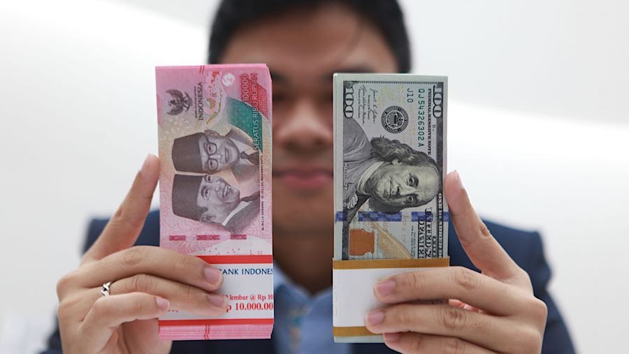Karyawan memperlihatkan uang rupiah dan dolas AS di salah satu bank di Jakarta, Senin (1/12/2025). (Bloomberg Technoz/Andrean Kristianto)
