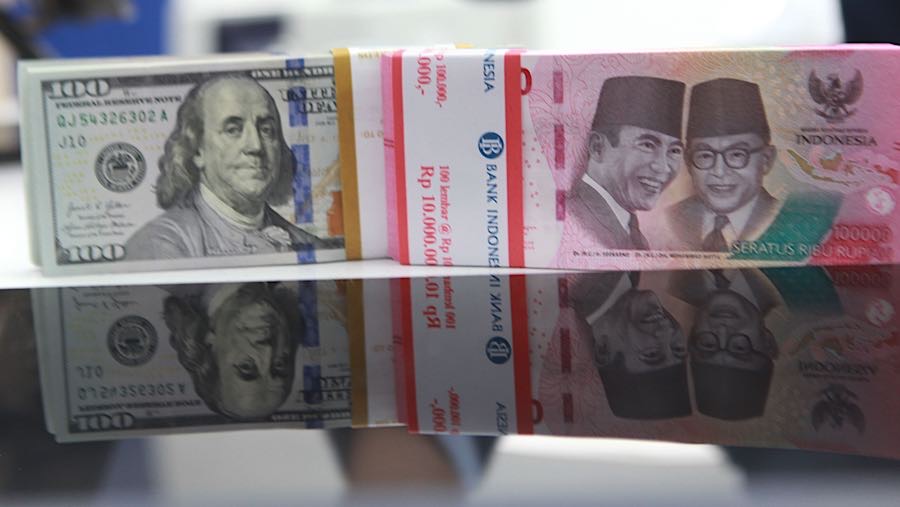 Karyawan merapihkan uang rupiah dan dolas AS di salah satu bank di Jakarta, Senin (1/12/2025). (Bloomberg Technoz/Andrean Kristianto)