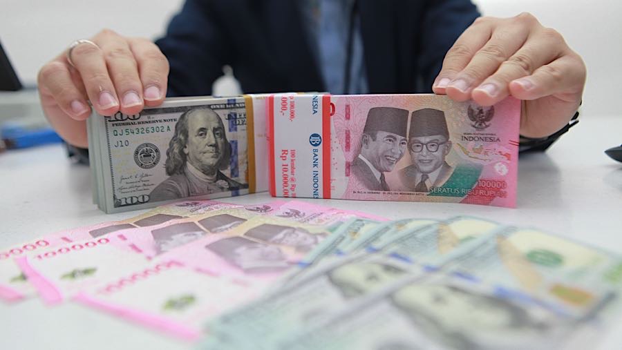 Karyawan merapihkan uang rupiah dan dolas AS di salah satu bank di Jakarta, Senin (1/12/2025). (Bloomberg Technoz/Andrean Kristianto)