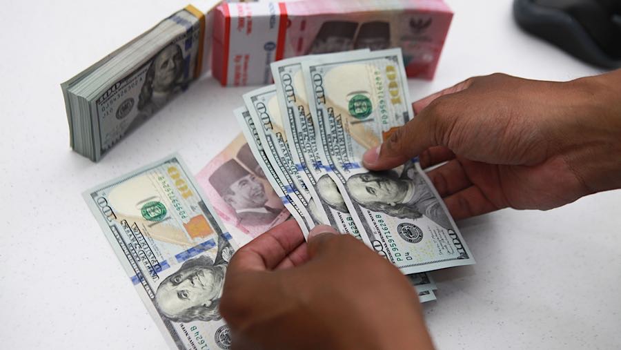Karyawan merapihkan uang rupiah dan dolas AS di salah satu bank di Jakarta, Senin (1/12/2025). (Bloomberg Technoz/Andrean Kristianto)