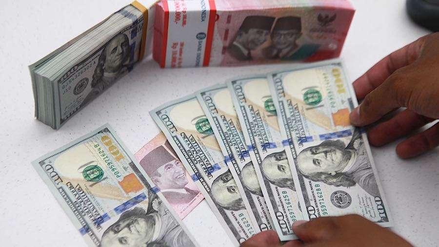 Karyawan merapihkan uang rupiah dan dolas AS di salah satu bank di Jakarta, Senin (1/12/2025). (Bloomberg Technoz/Andrean Kristianto)