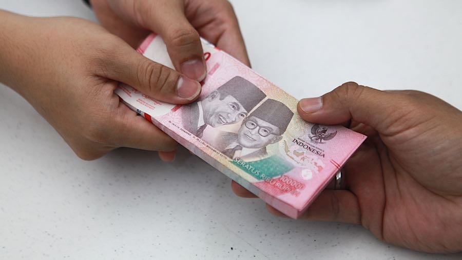 Karyawan memberikan uang rupiah kepada nasabah di salah satu bank di Jakarta, Senin (1/12/2025). (Bloomberg Technoz/Andrean Kristianto)