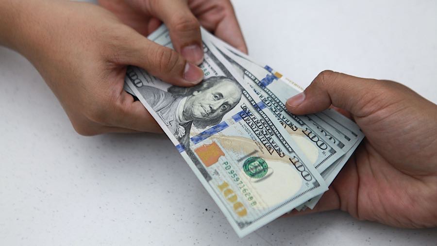 Karyawan memberikan uang dolar AS kepada nasabah di salah satu bank di Jakarta, Senin (1/12/2025). (Bloomberg Technoz/Andrean Kristianto)
