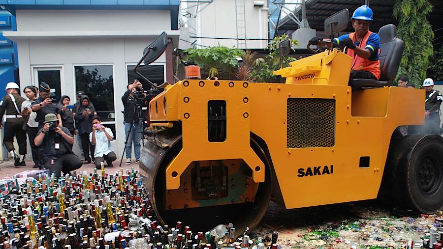 Petugas menggunakan alat berat memusnahkan minuman keras di Jakarta, Rabu (3/12/2025). (Bloomberg Technoz/ Andrean Kristianto)