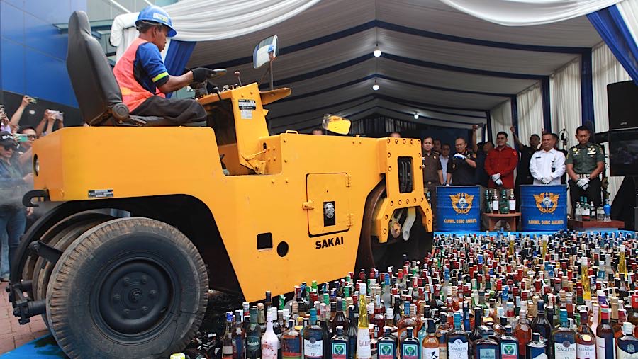 Petugas menggunakan alat berat memusnahkan minuman keras di Jakarta, Rabu (3/12/2025). (Bloomberg Technoz/ Andrean Kristianto)