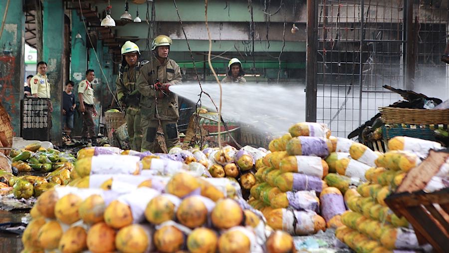 Petugas melakukan proses pendinginan saat kebakaran di Pasar Induk Kramat Jati, Senin (15/12/2025). (Bloomberg Technoz/Andrean Kristianto)