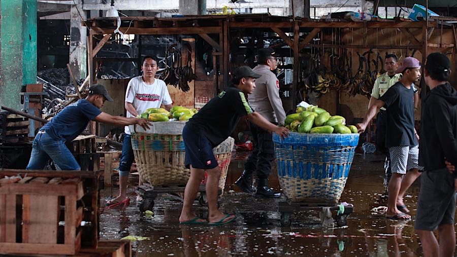 Saat api berhasil dipadamkan, pedagang terlihat merapihkan sisa buah yang masih terisisa usai kebakaran. (Bloomberg Technoz/Andrean Kristianto)