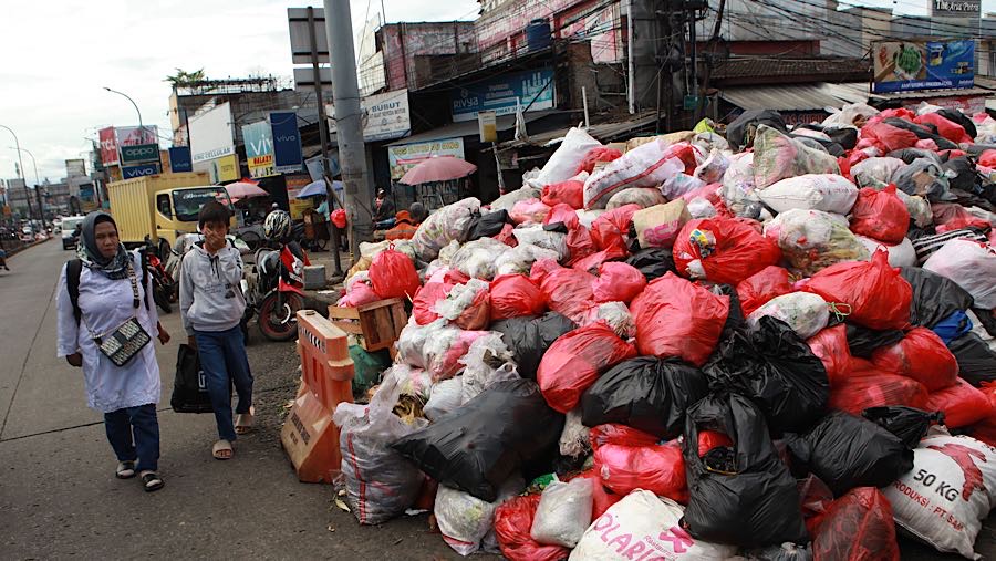 Warga menutup hidung untuk menghindari bau dari tumpukan sampah di Jln. Dewi Sartika, Tangsel, Rabu (17/12/2025). (Bloomberg Technoz/Andrean)