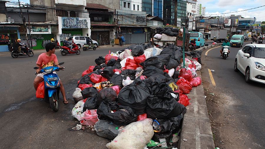 Warga melihat tumpukan sampah di Jalan Dewi Sartika, Tangerang Selatan, Banten, Rabu (17/12/2025). (Bloomberg Technoz/Andrean Kristianto)