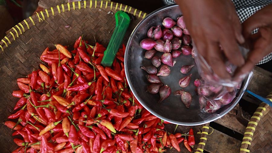 Pedagang membungkus bawang merah saat melayani pembeli di Pasar Minggu, Kamis (18/12/2025). (Bloomberg Technoz/ Andrean Kristianto)