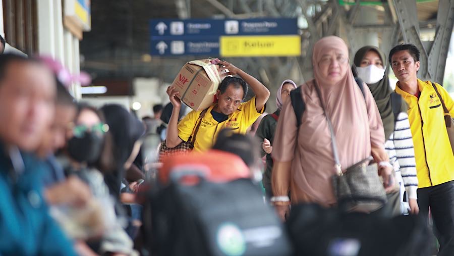 Porter membawa barang penumpang kereta api jarak jauh di Stasiun Pasar Senen, Senin (22/12/2025). (Bloomberg Technoz/Andrean Kristianto)