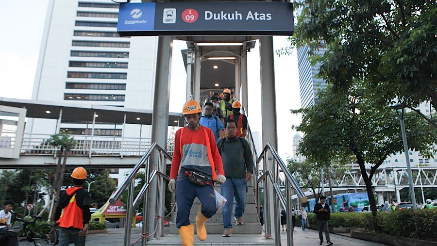 Pejalan kaki berjalan di jembatan penyeberangan orang di Jalan Jend. Sudirman, Selasa (23/12/2025). (Bloomberg Technoz/Andrean Kristianto)
