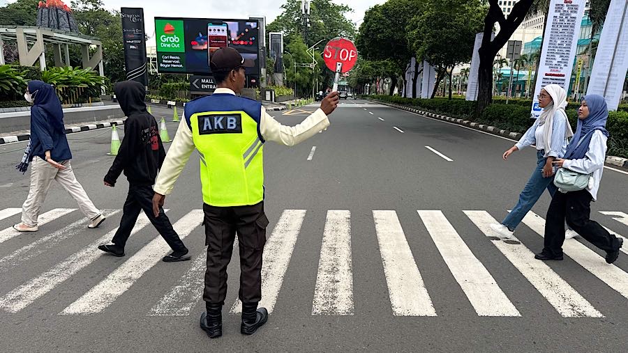 Pejalan kaki menyeberang di kawasan Senayan, Rabu (24/12/2025). (Bloomberg Technoz/Andrean Kristianto)