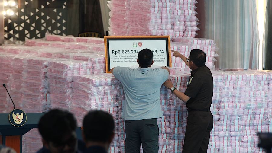 Petugas menata tumpukan uang penyelamatan keuangan negara dari hasil tindak pidana korupsi di Kejagung, Rabu (24/12/2025). (Bloomberg Technoz/Andre)